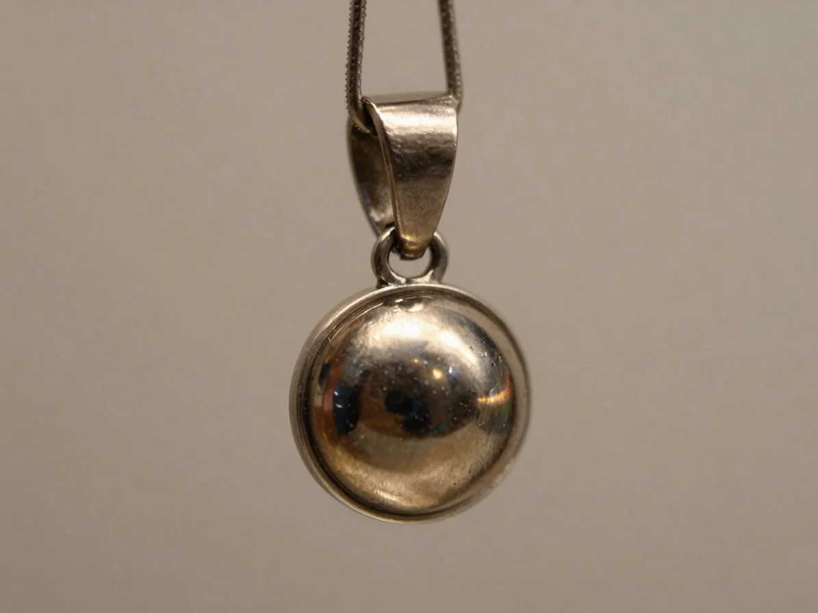 Macro product photograph of a clad base-metal pendant with a visi