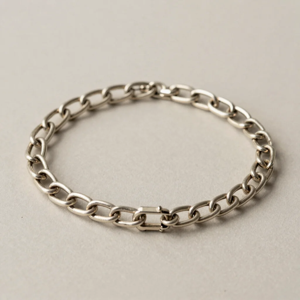 Studio photograph of a silver chain with a clasp arranged in a gentle curve, controlled reflections, neutral backdrop, 5